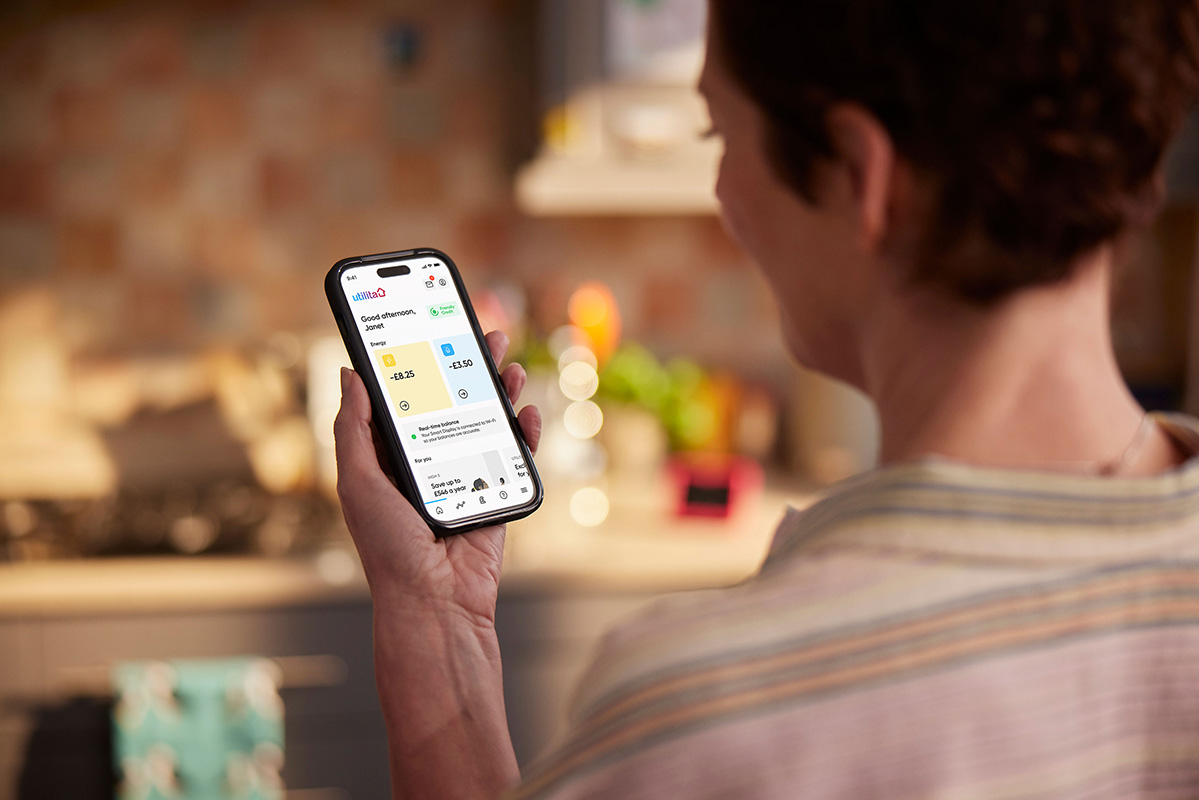 A woman using the My Utilita app on a phone, checking her gas & electricity usage with her Pay As You Go energy supplier.